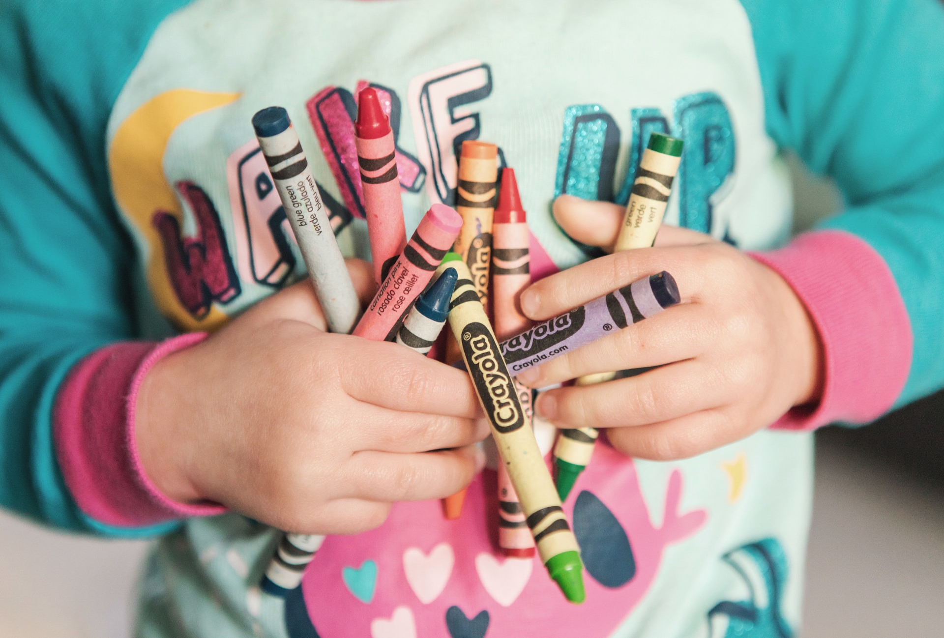 kid holding crayons to draw