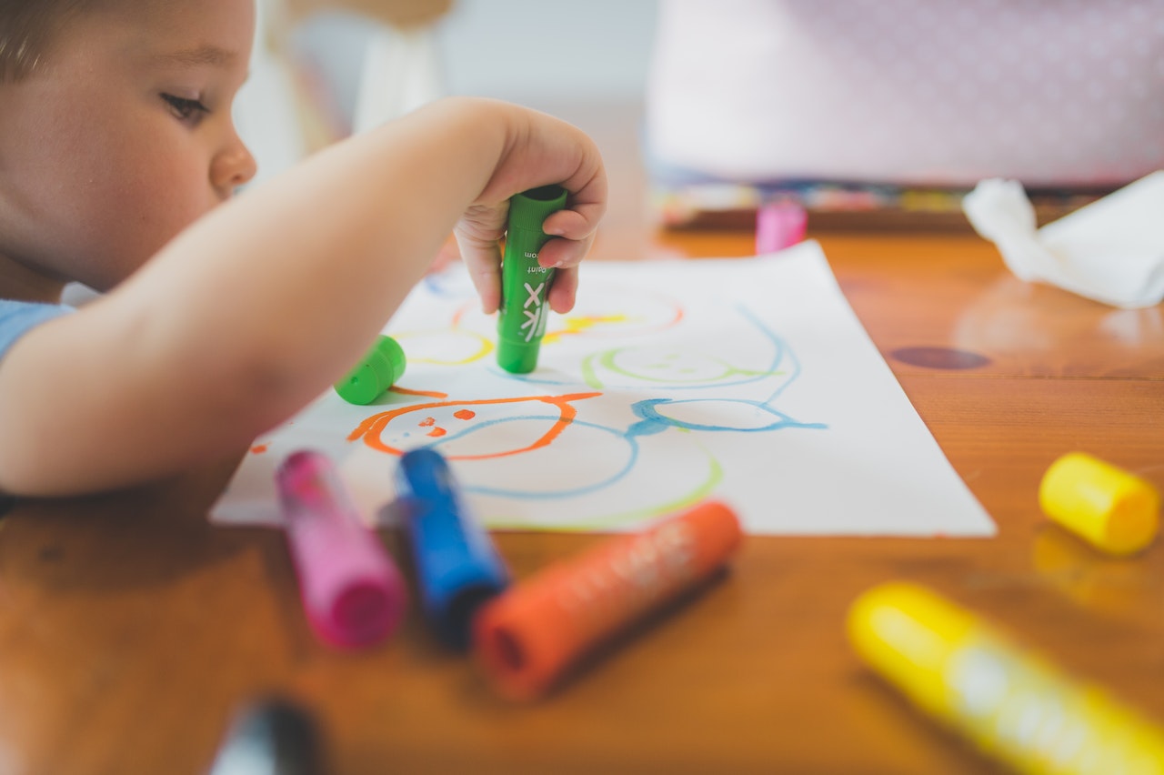 kid drawing with colorful crayons