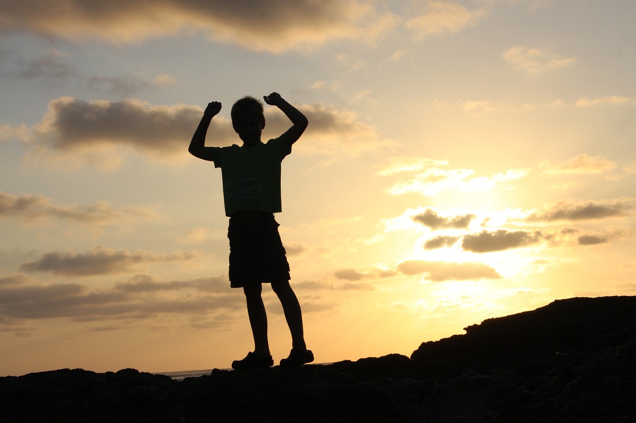 kid standing on the mountain successfully and happily