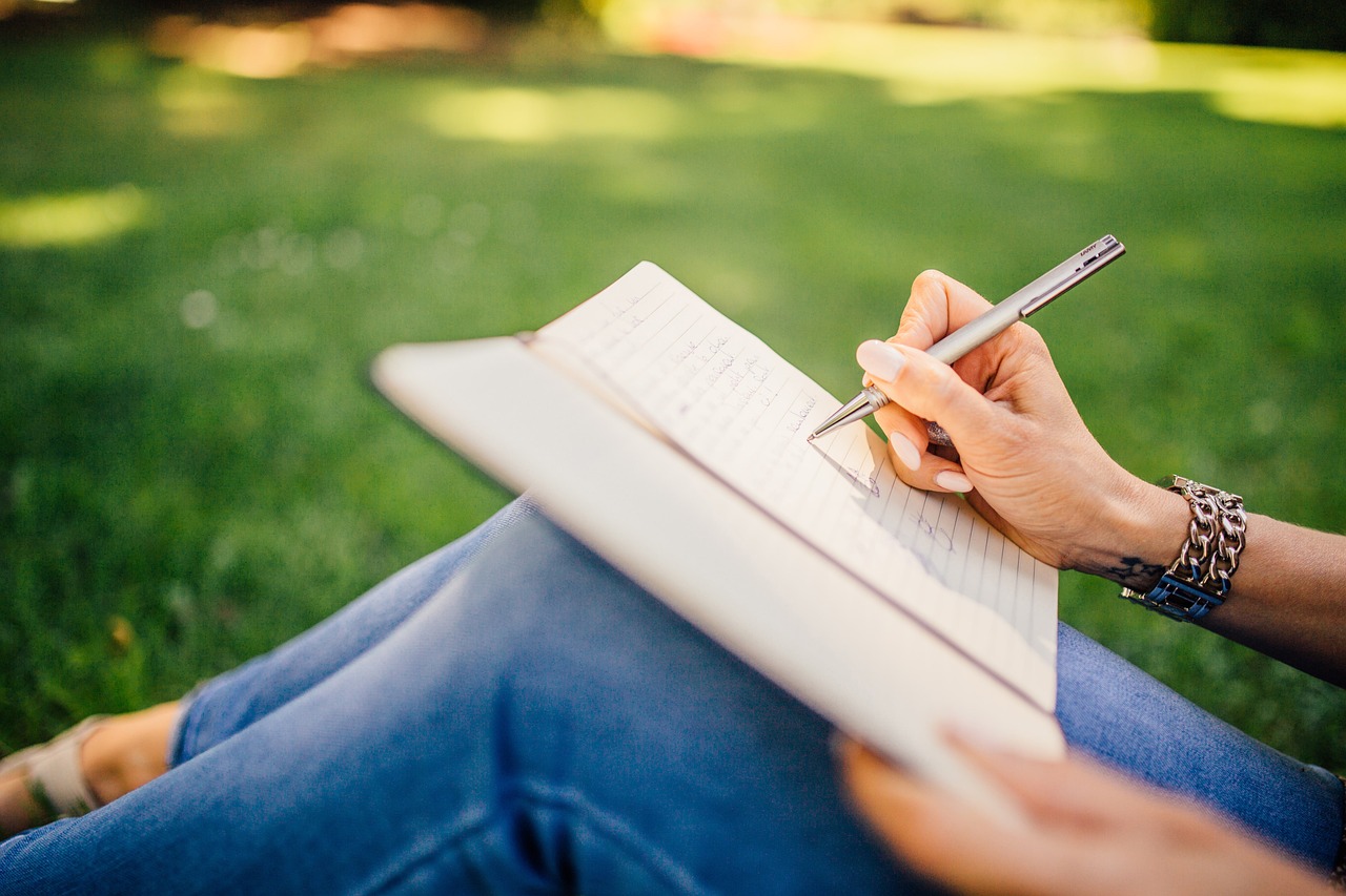 a girl writing on a grassland